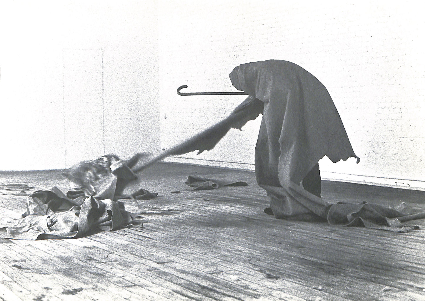 Interior page - CAROLINE TISDALL / JOSEPH BEUYS: COYOTE. Person in a hooded garment using a broom on a wooden floor.