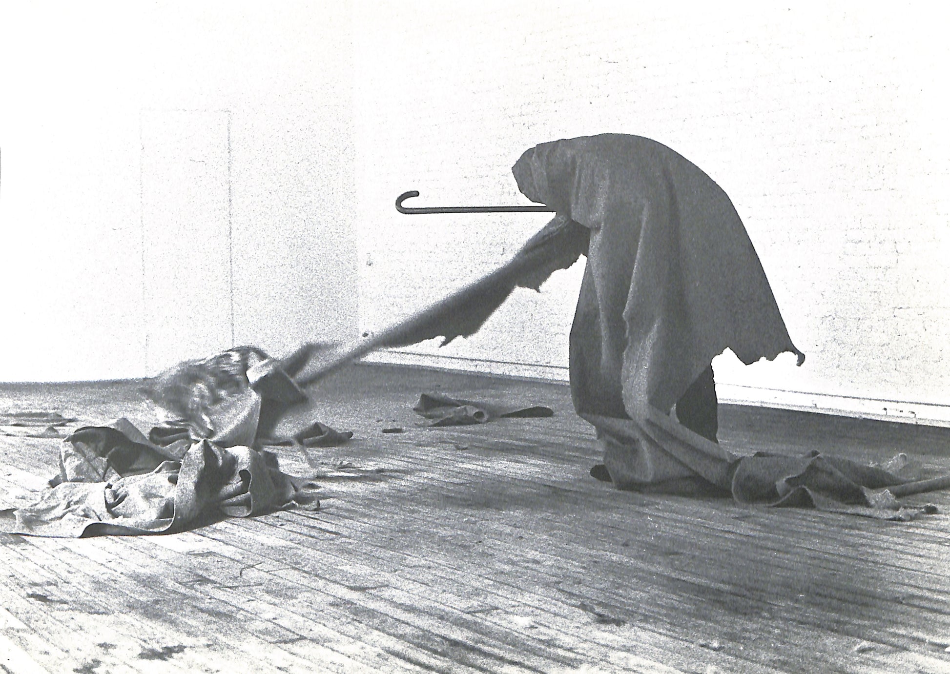 Interior page - CAROLINE TISDALL / JOSEPH BEUYS: COYOTE. Person in a hooded garment using a broom on a wooden floor.