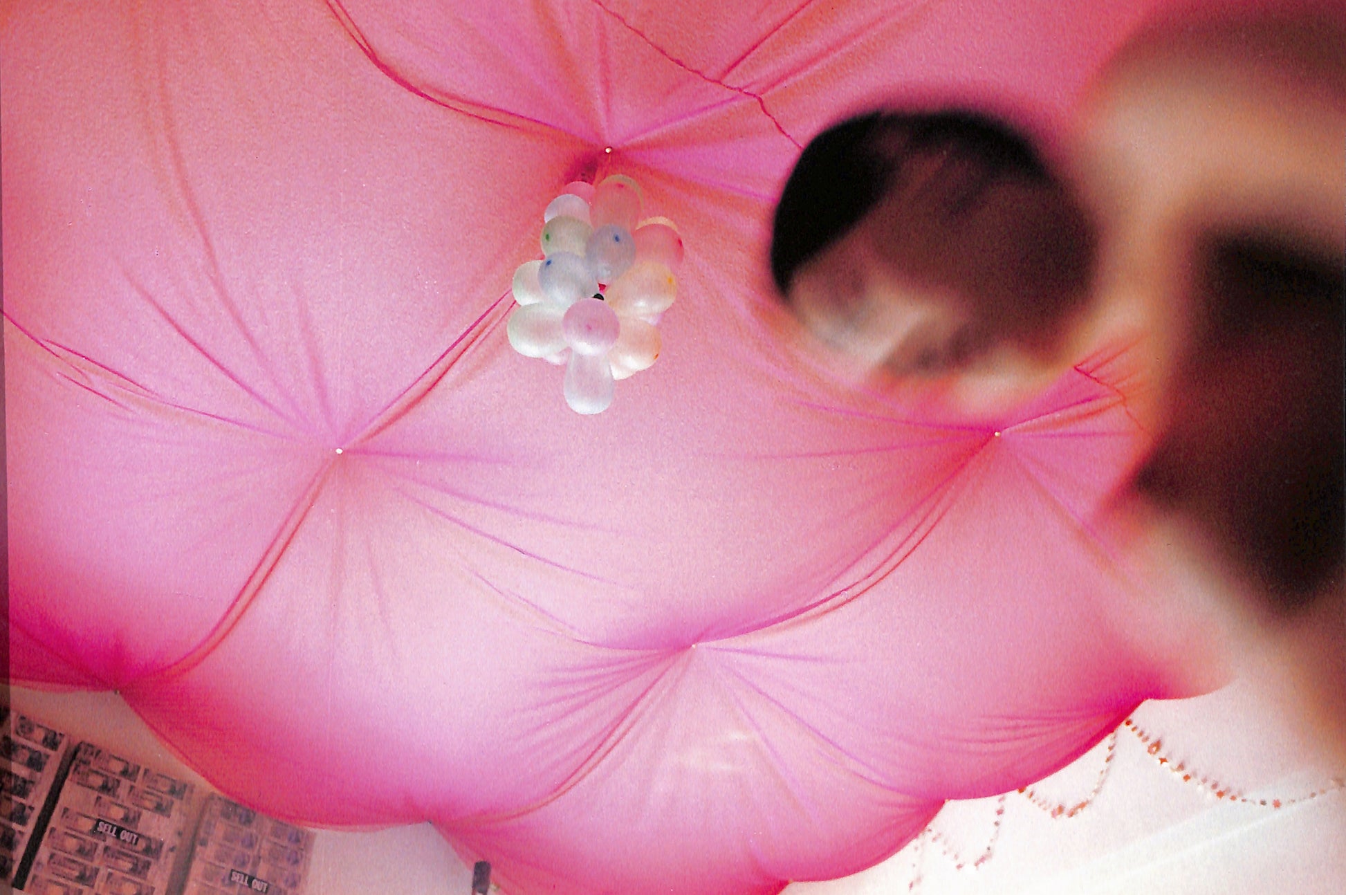 Interior shot - YURIE NAGASHIMA / YURIE NAGASHIMA. Close-up of a pink fabric with a floral decoration, possibly on a bed or sofa.