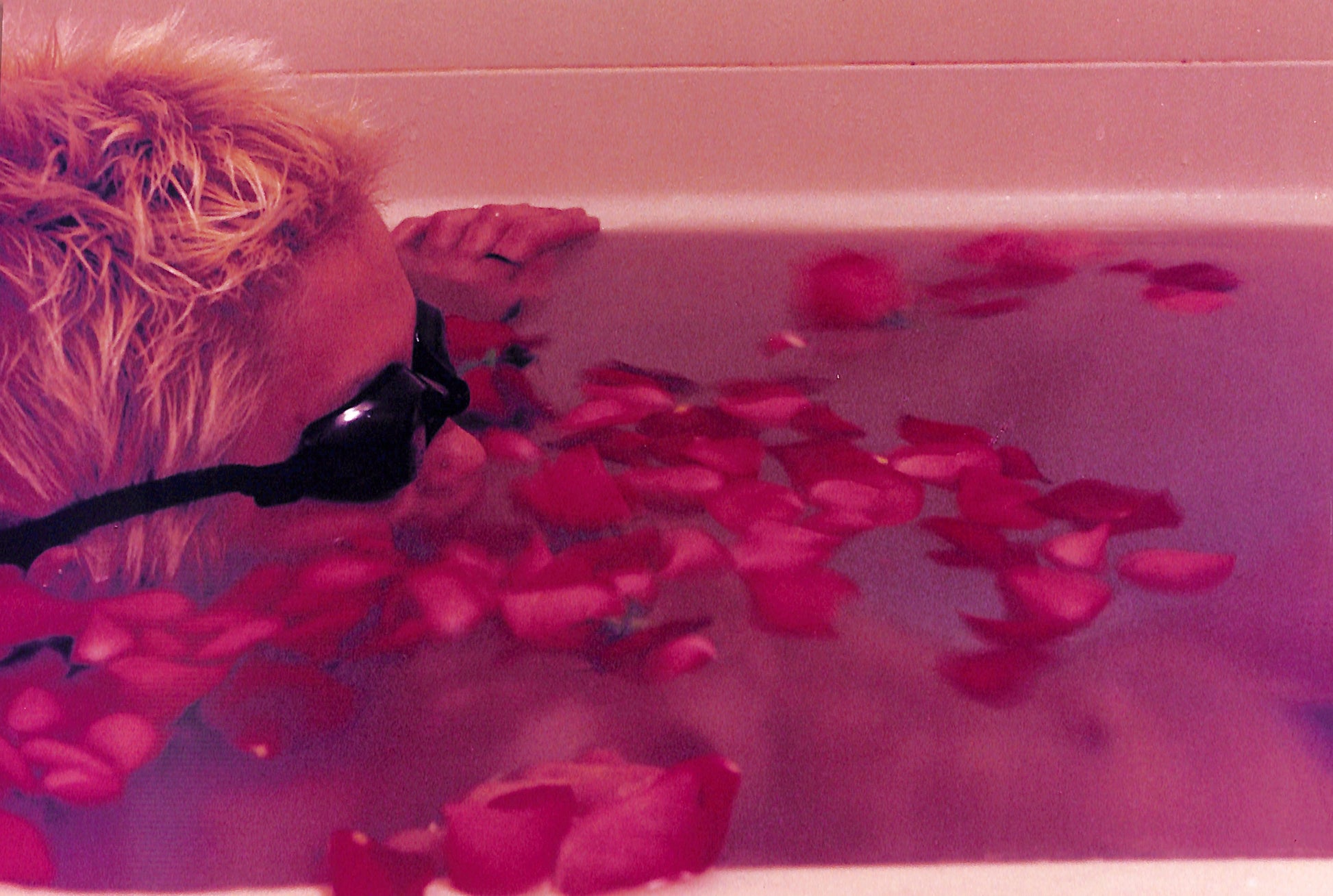 Interior shot -= YURIE NAGASHIMA / YURIE NAGASHIMA. Person with sunglasses in a bathtub filled with pink rose petals